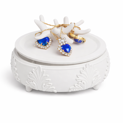 White jewelry box with blue heart-shaped earrings and gold rings on a white background