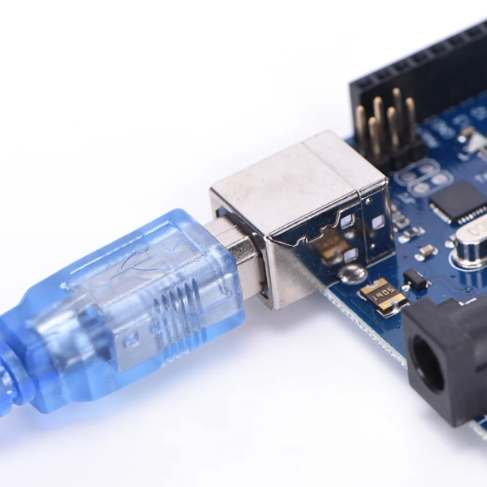 Close-up of a USB cable connected to an Arduino Uno board with components on a white background