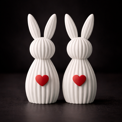 Two white rabbit-shaped vases with red hearts on a black background