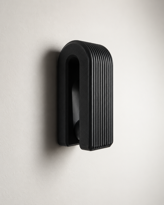 A modern black wall-mounted light fixture with a ribbed, vertically grooved rectangular design, shown mounted on a plain off-white wall.