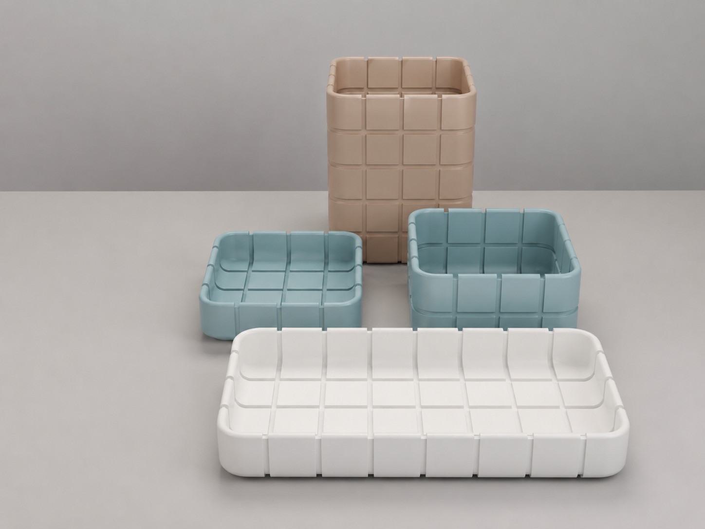 Four modular grid-patterned storage containers in white, light blue, and beige, arranged on a neutral gray surface and background.