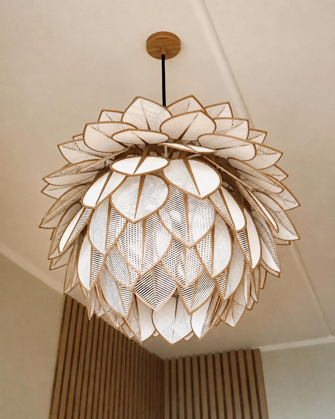 A modern lotus-shaped pendant chandelier with layered white petal-like shades and gold-toned metal frames, suspended from a ceiling in an indoor room setting.