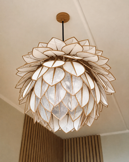 A modern lotus-shaped pendant chandelier with layered white petal-like shades and gold-toned metal frames, suspended from a ceiling in an indoor room setting.