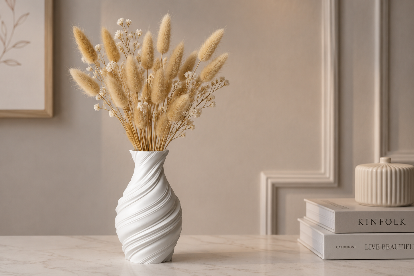 A white ceramic vase with a twisted spiral design, filled with dried bunny tail grass and small white flowers, set on a light marble tabletop in a styled interior setting.