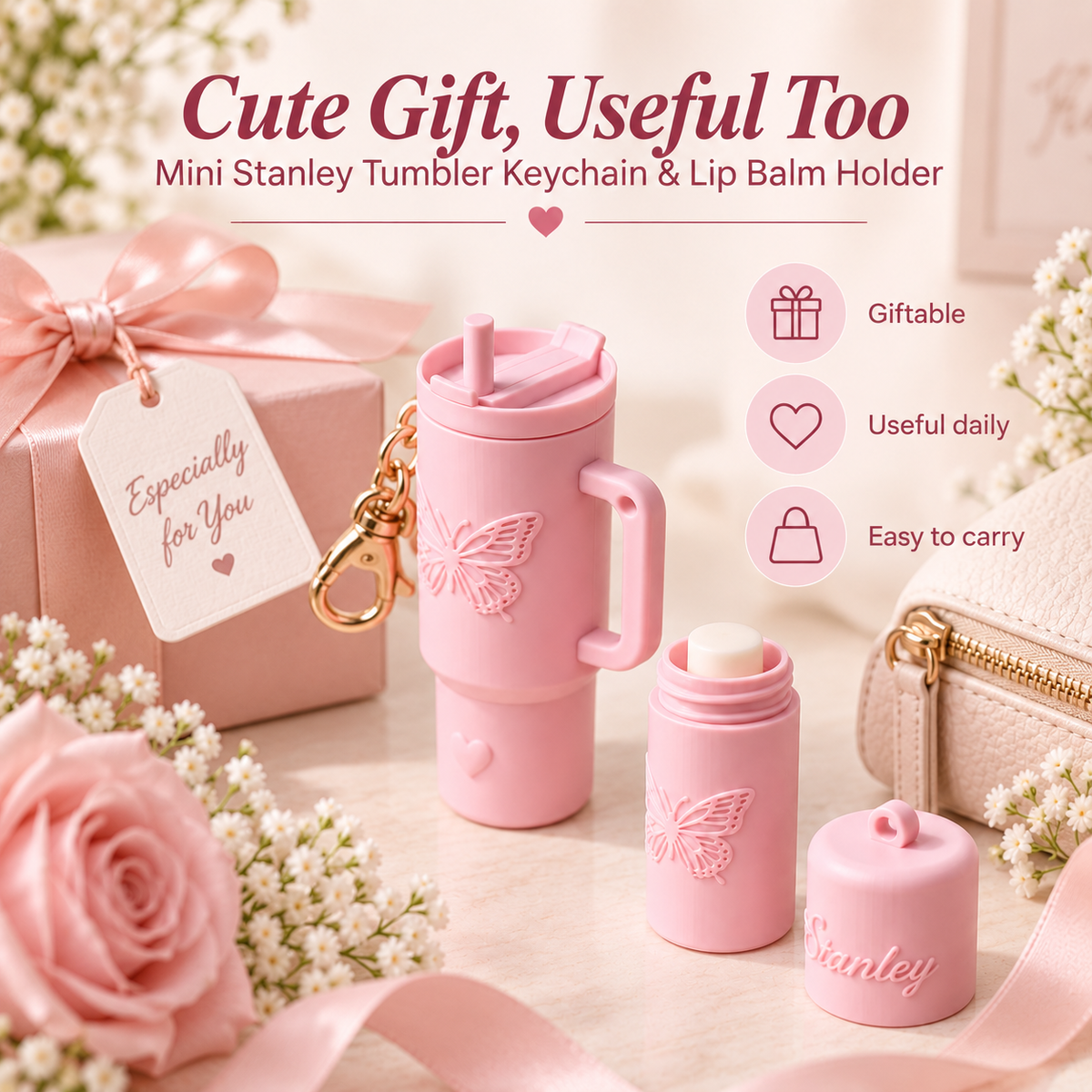 A pink mini Stanley tumbler keychain and lip balm holder set displayed on a light surface with decorative flowers, a gift box, and a small pouch. The set includes a handled tumbler with a butterfly embossing, a small lip balm container, its cap, and a gold keychain.