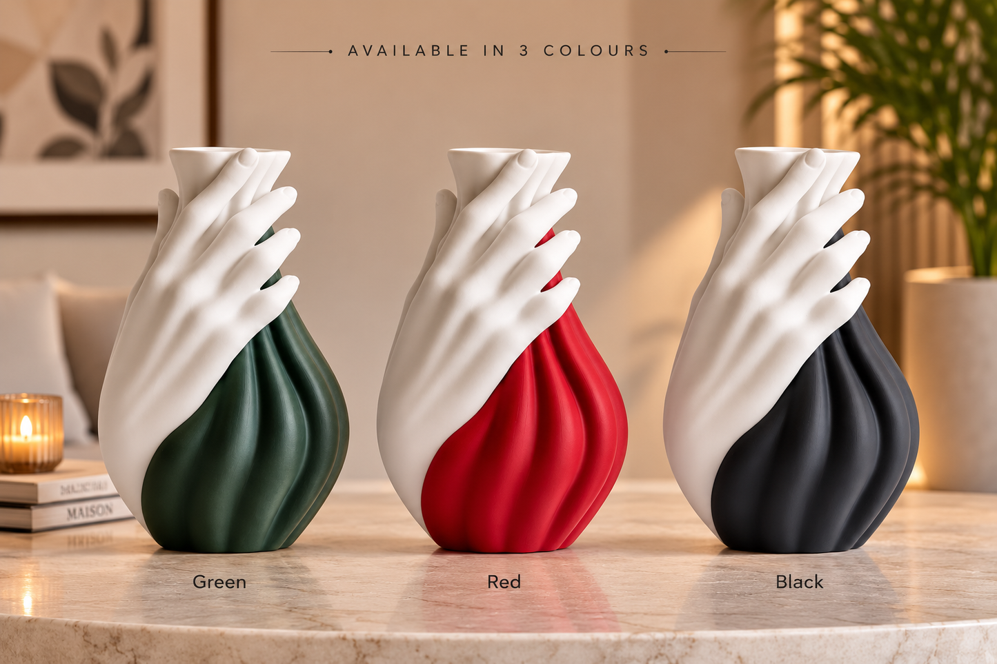 Three sculptural hand-shaped vases displayed on a marble surface in a softly lit interior. The left vase is dark green, the center vase is red, and the right vase is black, each with a white hand wrapping around the back.