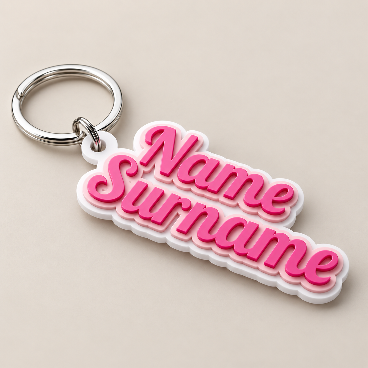 A customizable keychain featuring the words 'Name Surname' in 3D pink bubble letters with a white outline, attached to a silver metal split ring, set against a solid beige background.