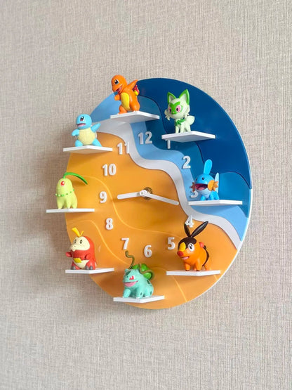 A circular wall clock featuring colorful Pokémon characters mounted on white shelf-like platforms around the clock face. The clock face is split diagonally between blue and orange, with white numbers and hands, shown against a light beige textured wall.