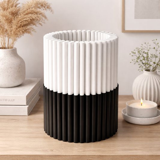 Black and white textured vase on a wooden surface with decorative elements.