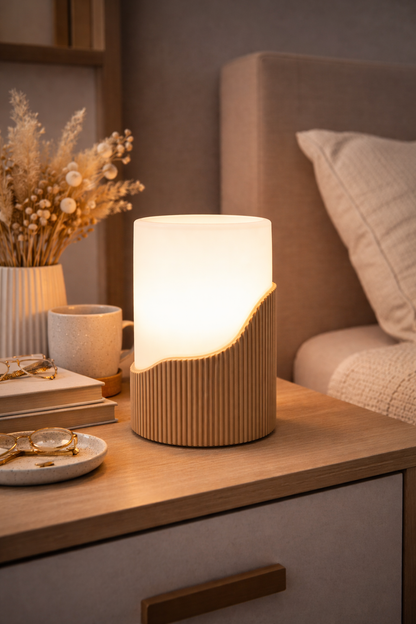 Table lamp on a nightstand with books, mug, and decorative items in a cozy bedroom setting.