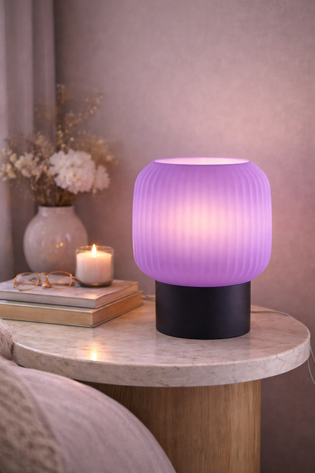 Purple table lamp on a marble side table with books and a candle