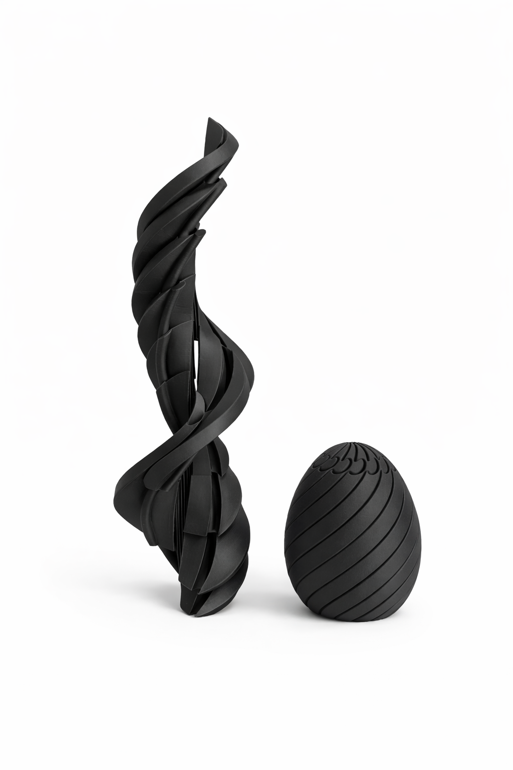 Black twisted sculpture and egg-shaped object on a white background