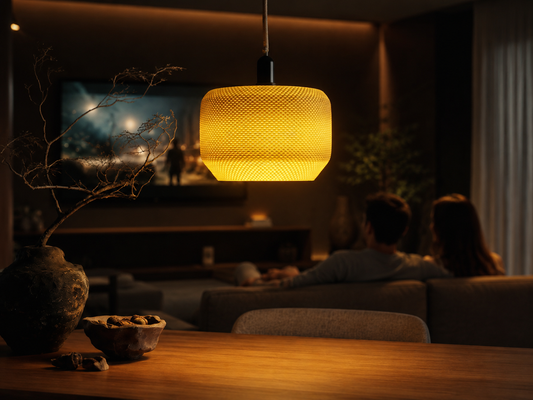 Living room with a glowing pendant light, TV, and people sitting on a couch.