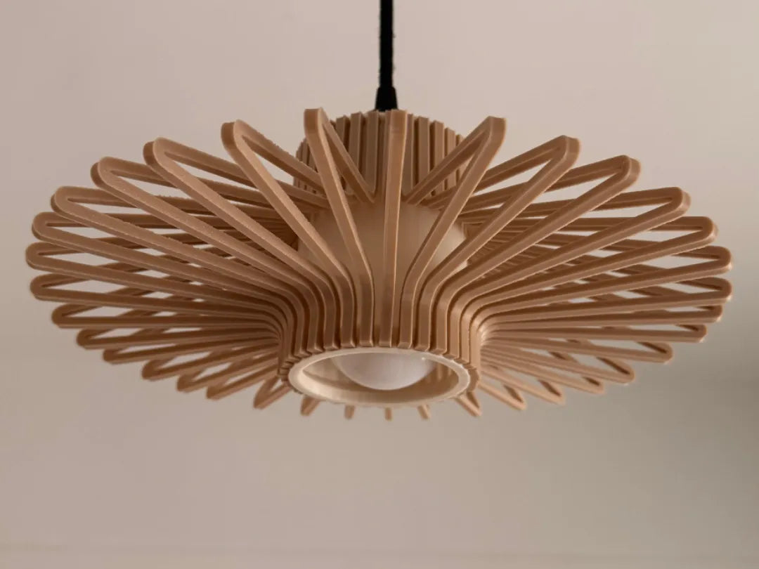 A modern radial pendant light fixture made of layered light wood slats, suspended from a black cord against a plain beige wall.