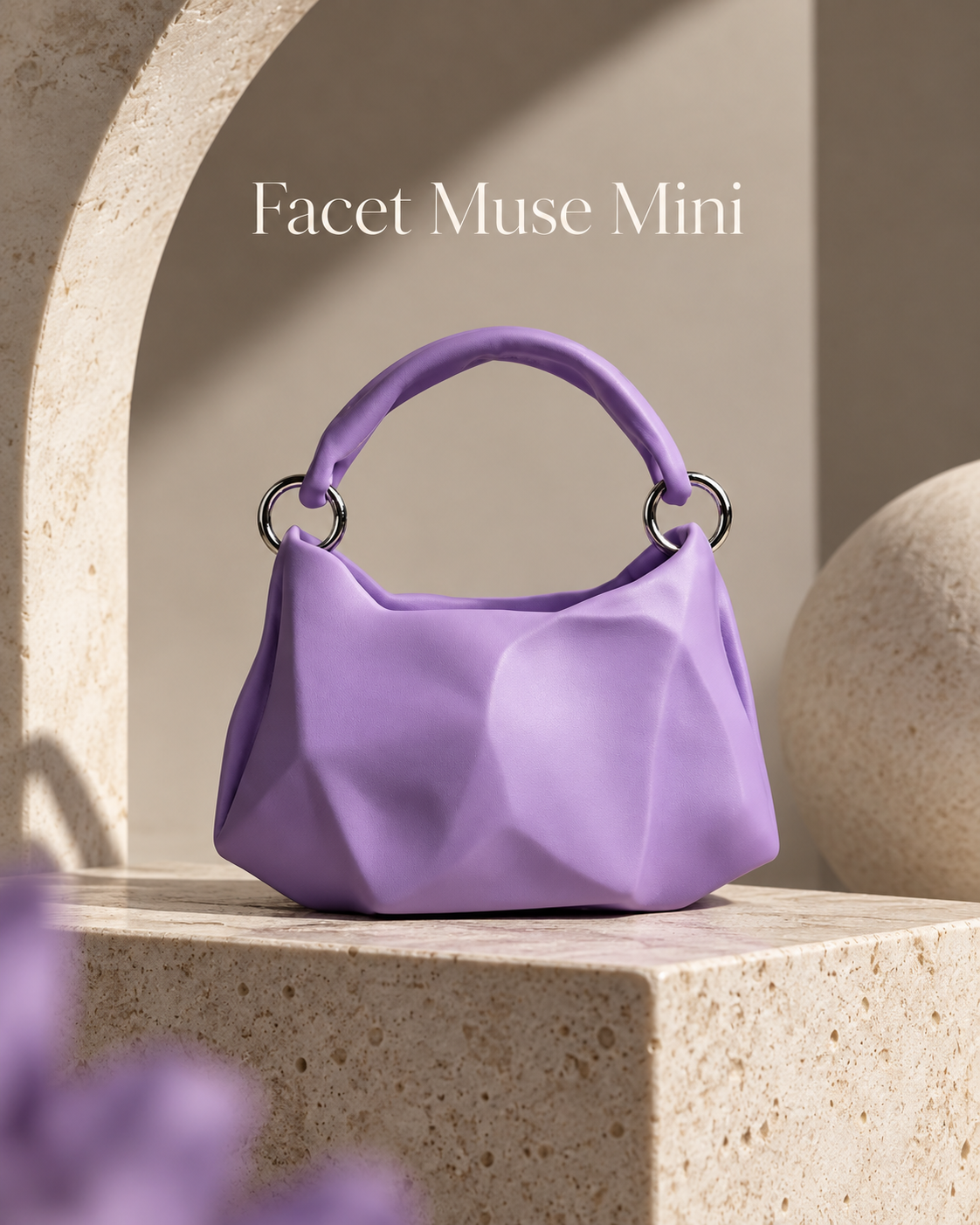 A small lavender purple handbag with a sculptural faceted design and a top handle, displayed on a stone pedestal in a minimalist architectural setting. The text 'Facet Muse Mini' is visible at the top.