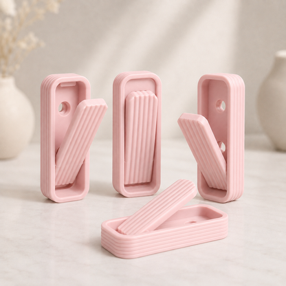 Four pink silicone door stoppers arranged on a light marble surface with soft-focus decorative vases in the background.
