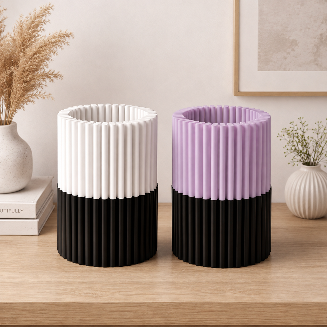 Two modern ribbed cylindrical containers on a wooden table, one in white and black and one in lavender and black, styled in a minimalist interior setting.