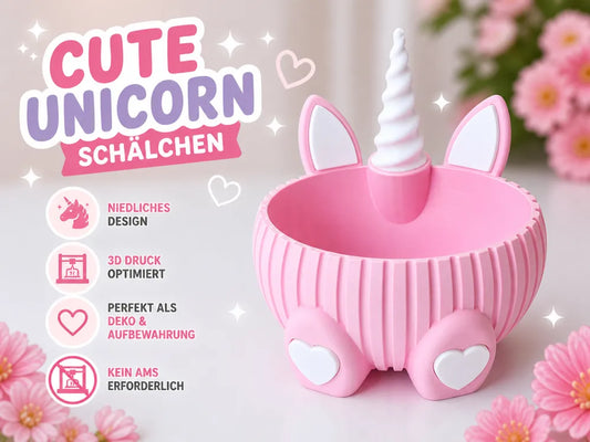 A pink unicorn-shaped storage box with a white horn and ears, shown on a soft light background with flowers and German promotional text on the left.